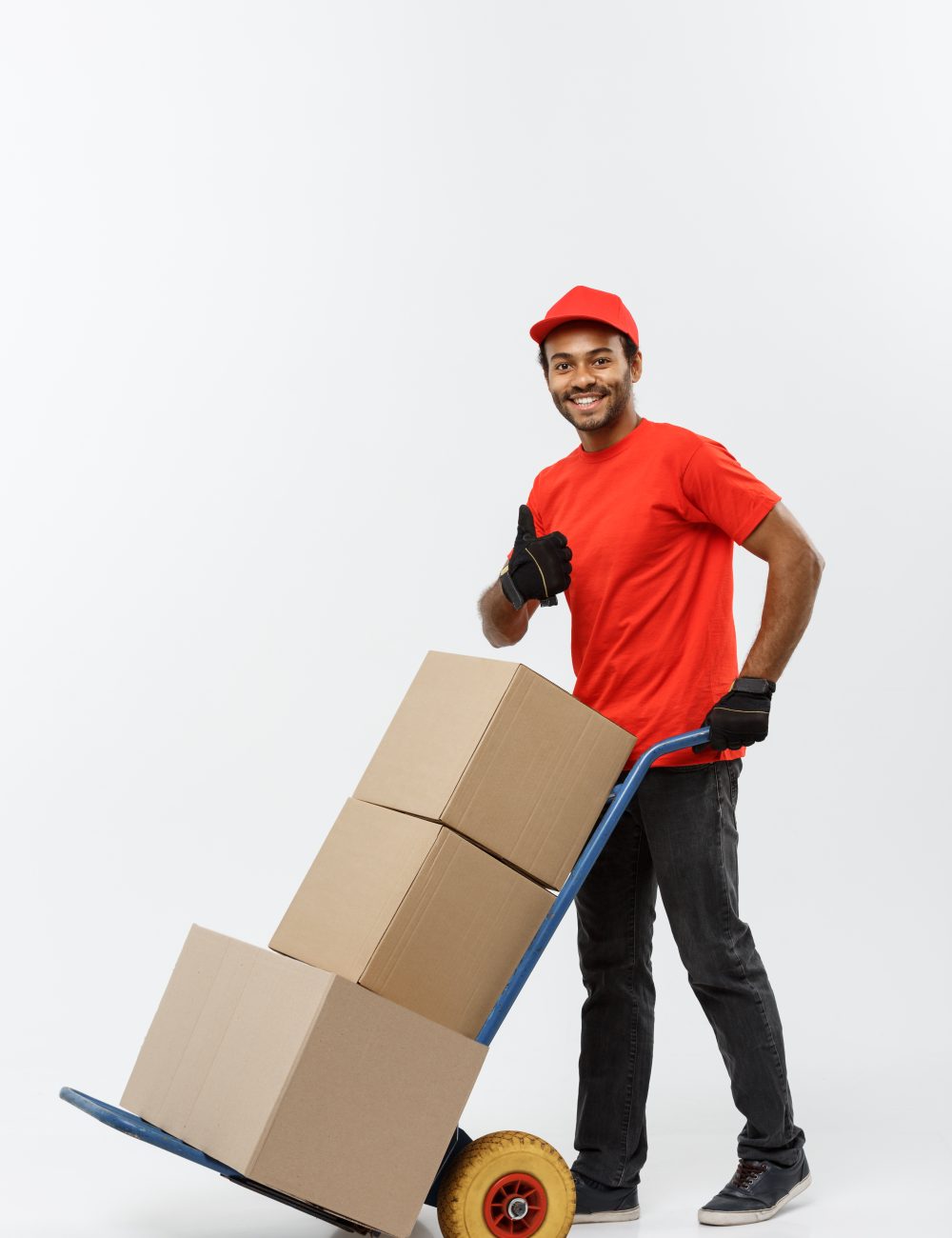 Delivery Concept - Portrait of Handsome African American delivery man or courier pushing hand truck with stack of boxes. Isolated on Grey studio Background. Copy Space.